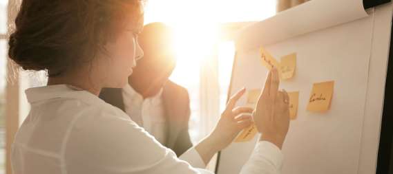 Shot of young business professionals brainstorming in a meeting. Businesswoman and businessman presenting their ideas on whiteboard.